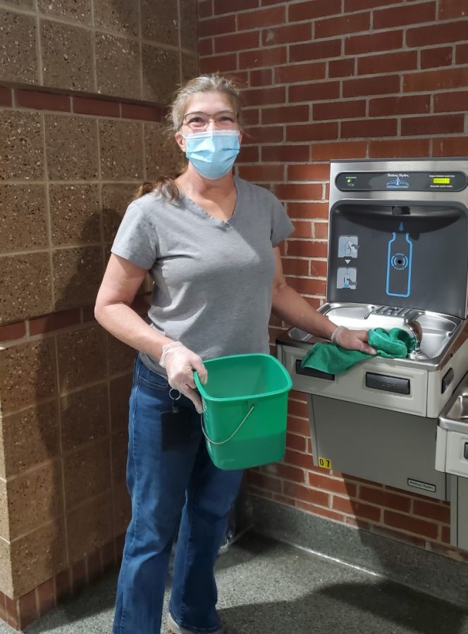 Custodian Ms. Amy Gabel wipes water fountain as part of cleaning routine